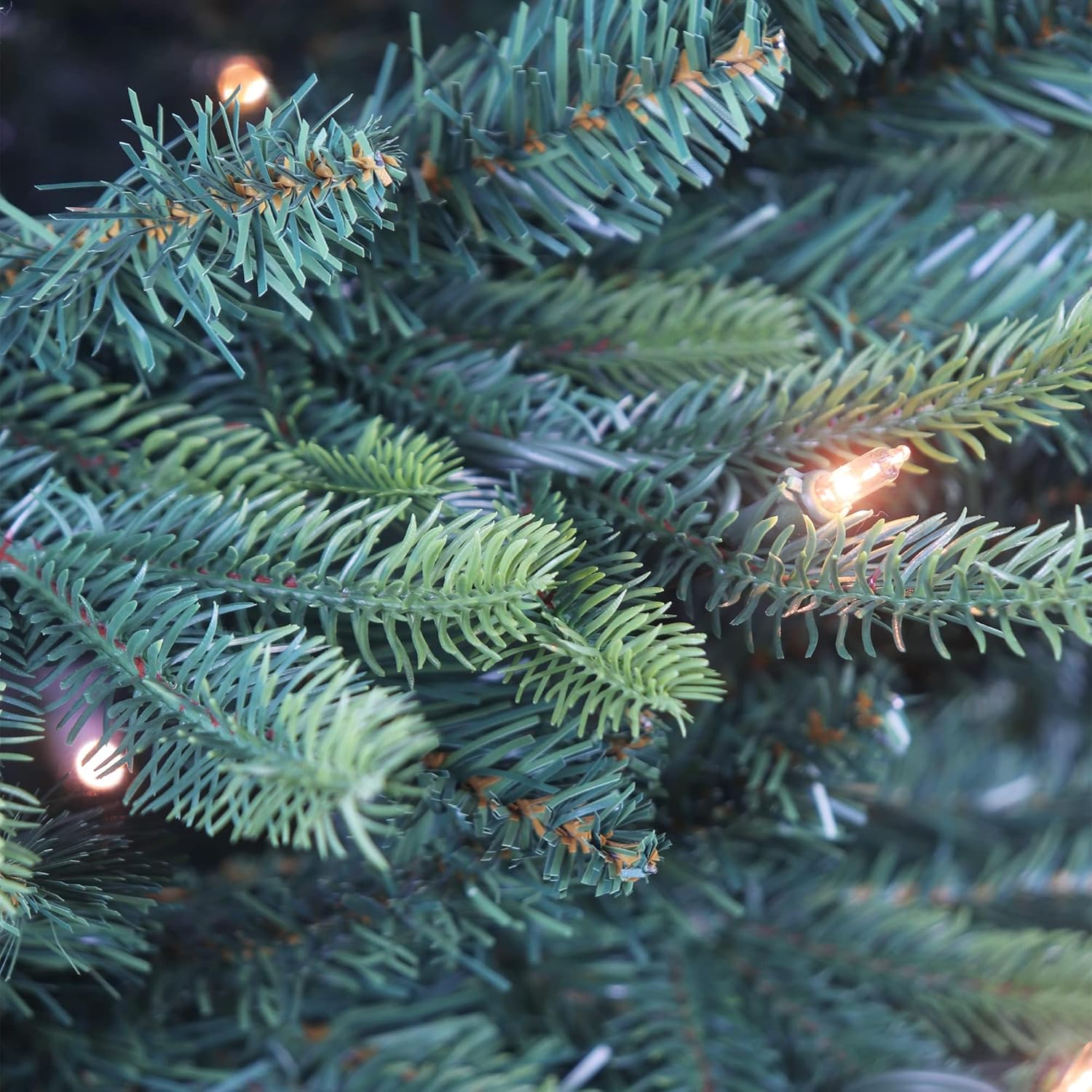 Close-up of the pre-lit Christmas tree's green branches and a warm clear light.