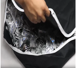Person unboxing a black bag containing the white decorated Christmas tree.