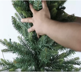 Person inserting the topper of an artificial Christmas tree