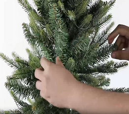 Person straightening the branches of the artificial Christmas tree