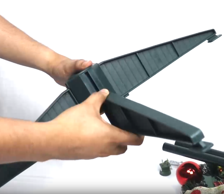 Person assembling a tree stand against a white background